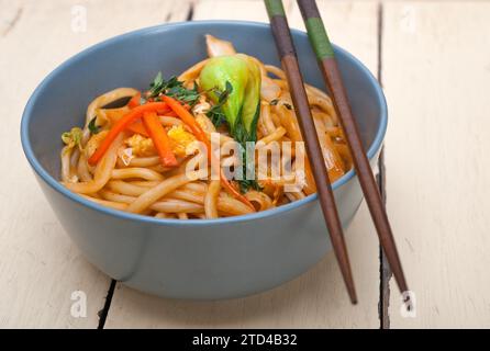 Spaghetti di ramen cinesi tirati a mano su una ciotola con bastone Foto Stock