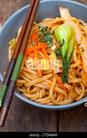 Spaghetti di ramen cinesi tirati a mano su una ciotola con bastone Foto Stock