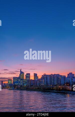 Vista in lontananza dei moderni edifici per uffici e grattacieli al tramonto su una riva della Senna nel quartiere degli affari di Parigi la Défense, Francia Foto Stock