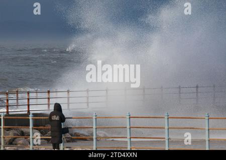 Grosvenor Breakwater, Heysham, Lancashire, 16 dicembre 2023, Walker osserva le onde che si infrangono sul Grosvenor Breakwater all'alta marea. Credito: PN News/Alamy Live News Foto Stock