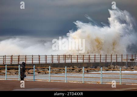 Grosvenor Breakwater, Heysham, Lancashire, 16 dicembre 2023, Walker osserva le onde che si infrangono sul Grosvenor Breakwater all'alta marea. Credito: PN News/Alamy Live News Foto Stock