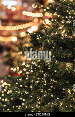 Rami verdi di un albero di Natale decorati con scintillanti luci dorate delle ghirlande. Dettagli natalizi all'interno. Foto Stock