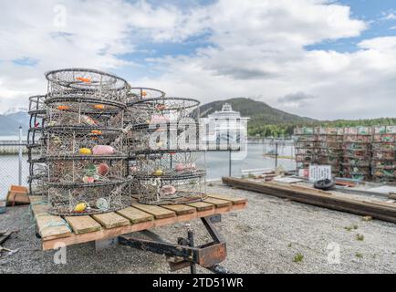 Vasi di aragosta - trappole impilate nel porto di Haines con una nave da crociera fuori fuoco ancorata a distanza, Haines, Alaska, USA Foto Stock