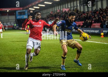 Salford, Regno Unito. 16 dicembre 2023.Huseyin Biler di Wimbledon cerca di bloccare Kelly N'mai di Salford City dal pallone durante la partita di Sky Bet League 2 tra Salford City e AFC Wimbledon a Moor Lane, Salford sabato 16 dicembre 2023. (Foto: Ian Charles | mi News) crediti: MI News & Sport /Alamy Live News Foto Stock