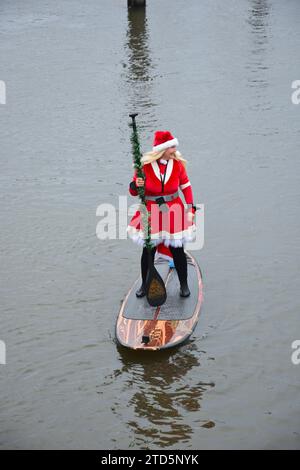 Lady paddle boarder sull'acqua vestita da Babbo Natale. Evento natalizio di paddle boarding organizzato dai BH Activity Junkies Foto Stock