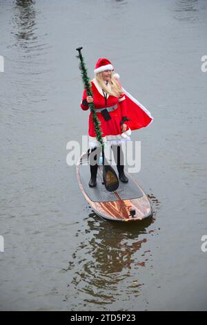 Lady paddle boarder sull'acqua vestita da Babbo Natale. Evento natalizio di paddle boarding organizzato dai BH Activity Junkies Foto Stock