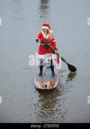 Lady paddle boarder sull'acqua vestita da Babbo Natale. Evento natalizio di paddle boarding organizzato dai BH Activity Junkies Foto Stock