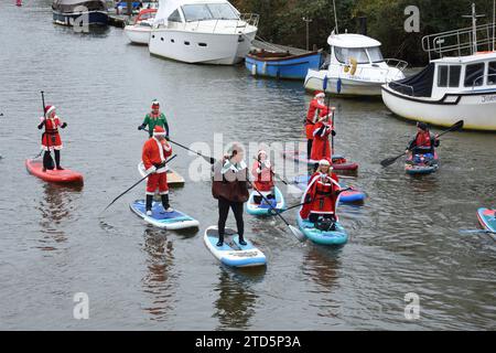 Tavole da paddle vestiti da Babbo Natale ed Elfi. Evento natalizio di paddle boarding organizzato dal BH Activity Junkieson sul fiume Stour a Christchurch, Regno Unito Foto Stock