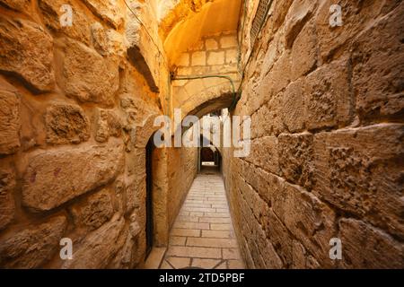 Uno stretto vicolo con archi e mura di pietra nel quartiere musulmano della città vecchia di Gerusalemme Foto Stock