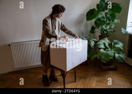 La ragazza vive uno stile di vita ecologico raccogliendo oggetti per riciclare il nastro adesivo della scatola di cartone. Foto Stock