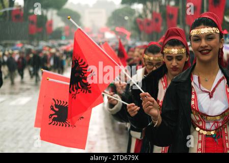 Tirana, Albania - 28 novembre 2023: Sulla via dei Martiri della Nazione, durante una giornata piovosa dell'indipendenza, le studentesse marciano in fila, sorridendo e vivendo Foto Stock