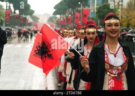 Tirana, Albania - 28 novembre 2023: Sulla via dei Martiri della Nazione, durante una giornata piovosa dell'indipendenza, le studentesse marciano in fila, sorridendo e vivendo Foto Stock