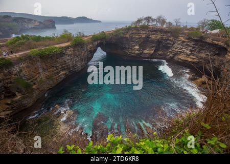 La pittoresca formazione rocciosa unica della spiaggia rotta e la spiaggia Kelingking sull'isola di Nusa Penida, Bali, Indonesia Foto Stock