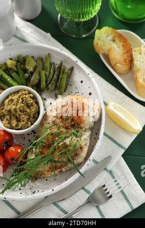 Gustoso pollo, verdure con dragoncello e pesto serviti su un tavolo verde, vista dall'alto Foto Stock