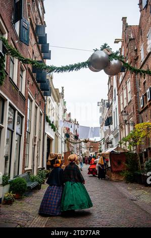 Due donne in costumi vittoriani sono viste camminare in una strada solitaria prima dell'inizio del Festival. Ogni anno, intorno a questa data, il mondo del XIX secolo dello scrittore inglese Charles Dickens rivive nella splendida città olandese di Deventer. Più di 950 personaggi dei famosi libri di Dickens Back to Life. Benestanti signore e signori con i migliori cappelli sfilano per le strade. Il paesaggio del festival è costituito da edifici storici, alberi di Natale e migliaia di piccole luci. Non solo per strada, ma anche dietro le finestre, nelle case e nei piccoli negozi e gallerie il romanticismo Foto Stock