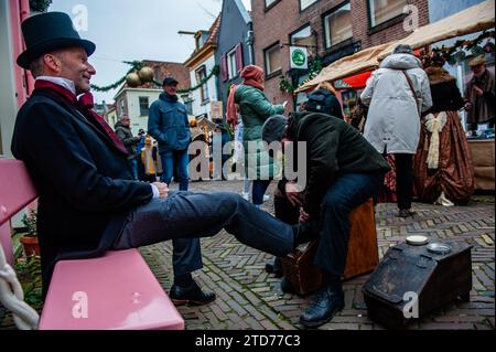 Un uomo con una tuta vittoriana si vede mentre pulisce le scarpe. Ogni anno, intorno a questa data, il mondo del XIX secolo dello scrittore inglese Charles Dickens rivive nella splendida città olandese di Deventer. Più di 950 personaggi dei famosi libri di Dickens Back to Life. Benestanti signore e signori con i migliori cappelli sfilano per le strade. Il paesaggio del festival è costituito da edifici storici, alberi di Natale e migliaia di piccole luci. Non solo per strada, ma anche dietro le finestre, nelle case e nei piccoli negozi e gallerie, il periodo romantico di Dickens è tornato alla vita. TH Foto Stock