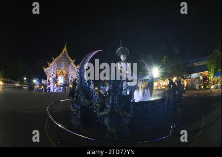 Scena notturna di Phra Upakut è una statua bianca perla posta al centro di una fontana. Di fronte alla cappella del tempio Wat Rong Suea Ten. Foto Stock