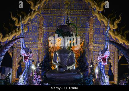 Scena notturna di Phra Upakut è una statua bianca perla posta al centro di una fontana. Di fronte alla cappella del tempio Wat Rong Suea Ten. Foto Stock