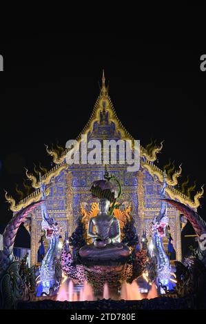 Scena notturna di Phra Upakut è una statua bianca perla posta al centro di una fontana. Di fronte alla cappella del tempio Wat Rong Suea Ten. Foto Stock