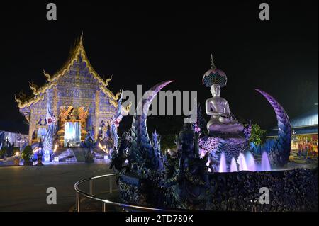 Scena notturna di Phra Upakut è una statua bianca perla posta al centro di una fontana. Di fronte alla cappella del tempio Wat Rong Suea Ten. Foto Stock