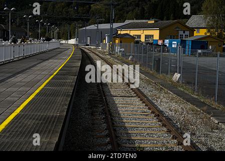 I binari portano dalla stazione ferroviaria verso le montagne in lontananza. Foto Stock