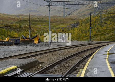 I binari portano dalla stazione ferroviaria verso le montagne in lontananza. Foto Stock