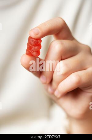 La gommmia masticabile porta vitamine e integratori. Una ragazza tiene in mano vitamine di un orso gommoso. Foto Stock