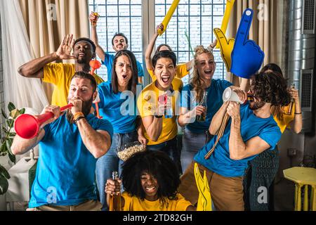 Tifosi di sport gioiosi multietnici che guardano la partita in TV a casa - sostenitori divertirsi sul divano per l'evento di competizione in TV - amici che celebrano la vittoria wh Foto Stock