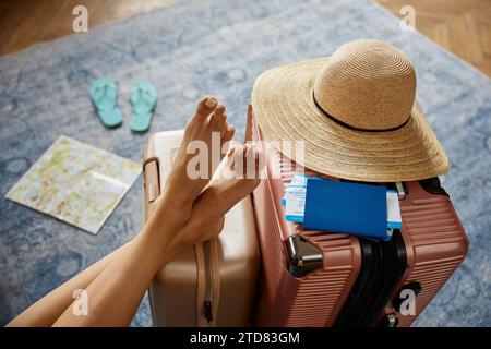 Gambe femminili slanciate su valigie da viaggio con biglietti per due Foto Stock