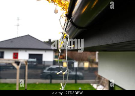 Installazione di luci a LED lungo la canalina intorno alla casa, decorando la casa per le vacanze. Foto Stock