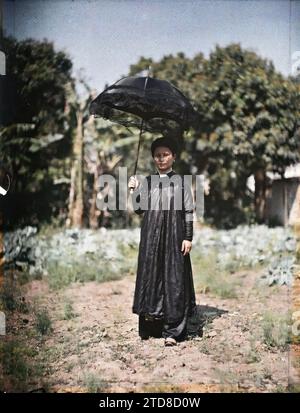 Tonkin, Indocina Una donna di classe benestante, che si rifugia sotto un ombrello nero ricoperto di pizzi, esseri umani, abbigliamento, alloggi, architettura, donna, Costume, Parasol, ombrello, parasole, ritratto, acconciatura, bretella di fissaggio, Parco, Giardino, Indocina, Tonchino, donne indigene, classe superiore, elegante giovane donna nel giardino pubblico, Tonchino, 01/09/1915 - 30/11/1915, occupato, Léon, fotografo Léon occupato en Indochine, Autochrome, foto, vetro, Autochrome, foto, positivo, verticale, dimensioni 9 x 12 cm Foto Stock