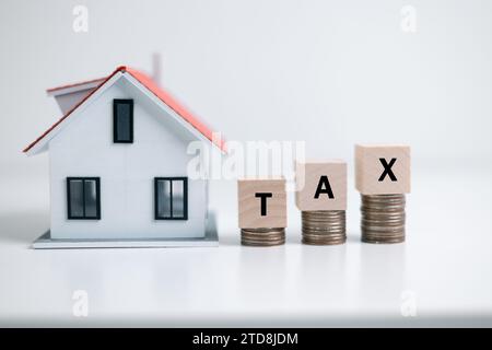 Concetto di pagamento dell'imposta statale sulle proprietà. Tasse di proprietà blocchi di legno con Una casa in miniatura. modello di casa, ipoteca che carica immobili con prestito Foto Stock