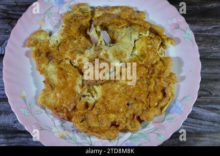 Una frittata o omelette, un piatto a base di uova, fritto con burro o olio in padella, omelette con fette di cipolle, salate e con peppe nero Foto Stock