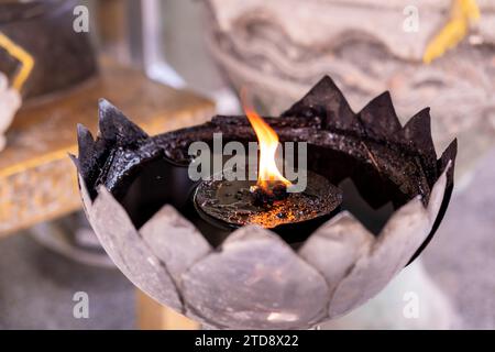 Fiamma di candela gialla che brucia, olio che riempie di candela di metallo di stile tailandese nel tempio buddista Foto Stock