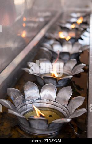 Fiamma di candela gialla che brucia, olio che riempie di candela di metallo di stile tailandese nel tempio buddista Foto Stock