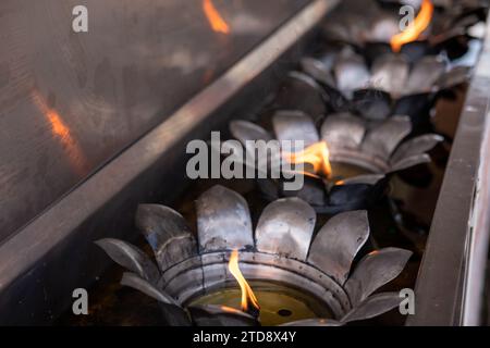 Fiamma di candela gialla che brucia, olio che riempie di candela di metallo di stile tailandese nel tempio buddista Foto Stock