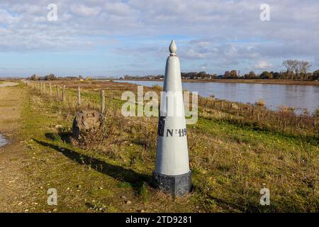 Riserva naturale belga De Wissen con un marcatore di confine tra Belgio e Olanda, fiume Maas sullo sfondo nebbioso, soleggiata giornata autunnale a Dilsen-Stokkem, Foto Stock