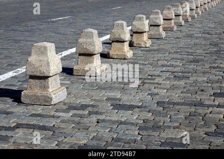 Barriera dalla lunga linea di piramidi di granito sulla vista laterale della pavimentazione stradale Foto Stock