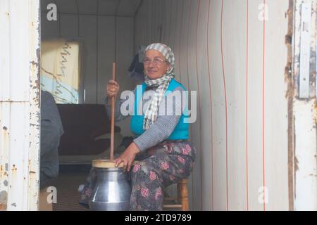 Donna che fa formaggio con metodi primitivi nel villaggio. Foto Stock