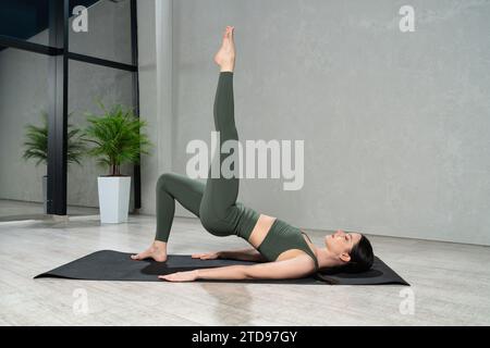 Donna sportiva che riposa in un ponte con una gamba in posa di yoga. Foto Stock
