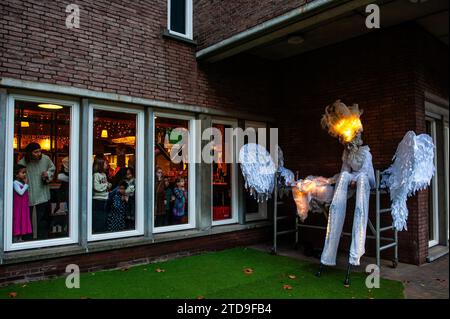 Nijmegen, Paesi Bassi. 16 dicembre 2023. Una donna si prepara sotto l'occhio vigile di un gruppo di bambini. La stagione natalizia è iniziata a Nijmegen con una bella sfilata invernale composta da un gruppo di artisti acrobatici che camminano su palafitte caratterizzate da creature fantasy. Una volta arrivato a Plein 1944, Erik van Zanten, presidente della "Casa per il centro città", e il consigliere John Brom aprirono le settimane invernali di Nijmegen con l'illuminazione di un albero di Natale alto dieci metri. (Foto di Ana Fernandez/SOPA Images/Sipa USA) credito: SIPA USA/Alamy Live News Foto Stock