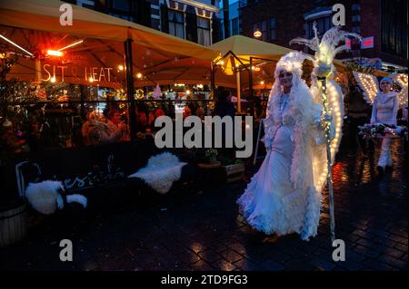 Nijmegen, Paesi Bassi. 16 dicembre 2023. Le persone sedute sulle terrazze guardano la parata che passa. La stagione natalizia è iniziata a Nijmegen con una bella sfilata invernale composta da un gruppo di artisti acrobatici che camminano su palafitte caratterizzate da creature fantasy. Una volta arrivato a Plein 1944, Erik van Zanten, presidente della "Casa per il centro città", e il consigliere John Brom aprirono le settimane invernali di Nijmegen con l'illuminazione di un albero di Natale alto dieci metri. (Foto di Ana Fernandez/SOPA Images/Sipa USA) credito: SIPA USA/Alamy Live News Foto Stock