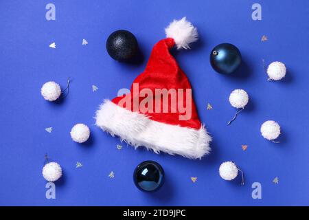 Cappello di Babbo Natale con palle di Natale e coriandoli su sfondo blu Foto Stock