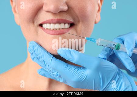 Bella donna matura che riceve l'iniezione su sfondo blu, primo piano Foto Stock