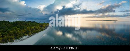 L'alba illumina la remota isola di Koon vicino a Seram, Indonesia. Le barriere coralline di quest'isola, e i mari circostanti, supportano un'elevata biodiversità marina. Foto Stock