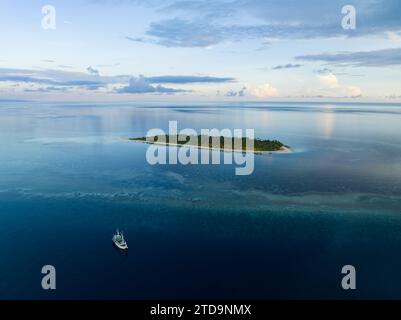 L'alba illumina la remota isola di Koon vicino a Seram, Indonesia. Le barriere coralline di quest'isola, e i mari circostanti, supportano un'elevata biodiversità marina. Foto Stock