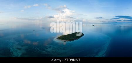 L'alba illumina la remota isola di Koon vicino a Seram, Indonesia. Le barriere coralline di quest'isola, e i mari circostanti, supportano un'elevata biodiversità marina. Foto Stock