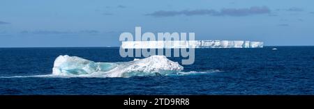 Antartide, Isole Orcadi meridionali. Iceberg con grande iceberg tabulare in lontananza galleggiante vicino alle Orcadi. Foto Stock