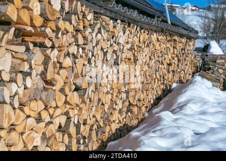 Deposito della legna da ardere per l'inverno sotto un capannone all'aperto in un luogo innevato d'inverno. Foto Stock