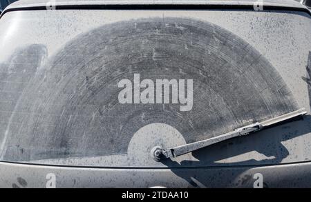 finestrino posteriore della vettura polveroso con tracce di tergicristallo su uno strato di sporco Foto Stock